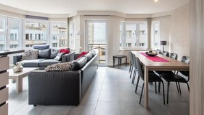 A modern apartment with a living area, dining space, and large windows offering views of the city. - Apartment in Ostend near Sandy Beaches (Oostende)