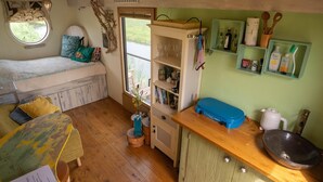 A cozy room with a bed, a small table, a window, and a shelf with toiletries. - Apartment in Netherlands near the Coast ('t Zand)