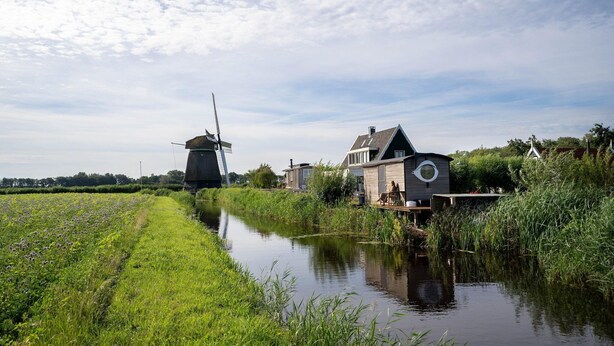A canal with a windmill and a house with a circular window. - Apartment in Netherlands near the Coast ('t Zand)