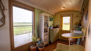 A compact kitchen with a large window, wooden flooring, and a small dining table. - Apartment in Netherlands near the Coast ('t Zand)