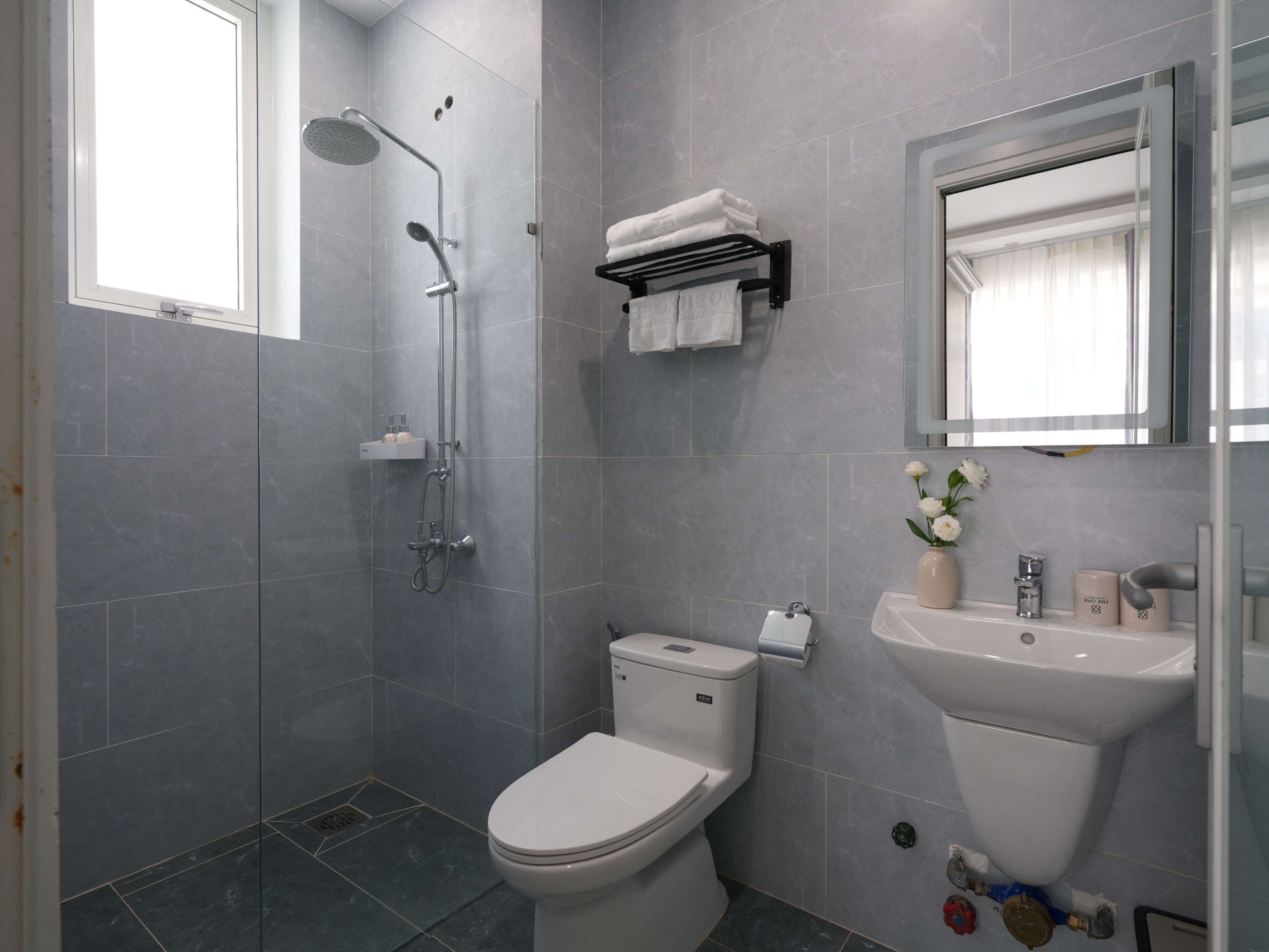 A modern bathroom with a shower, toilet, sink, and a mirror.