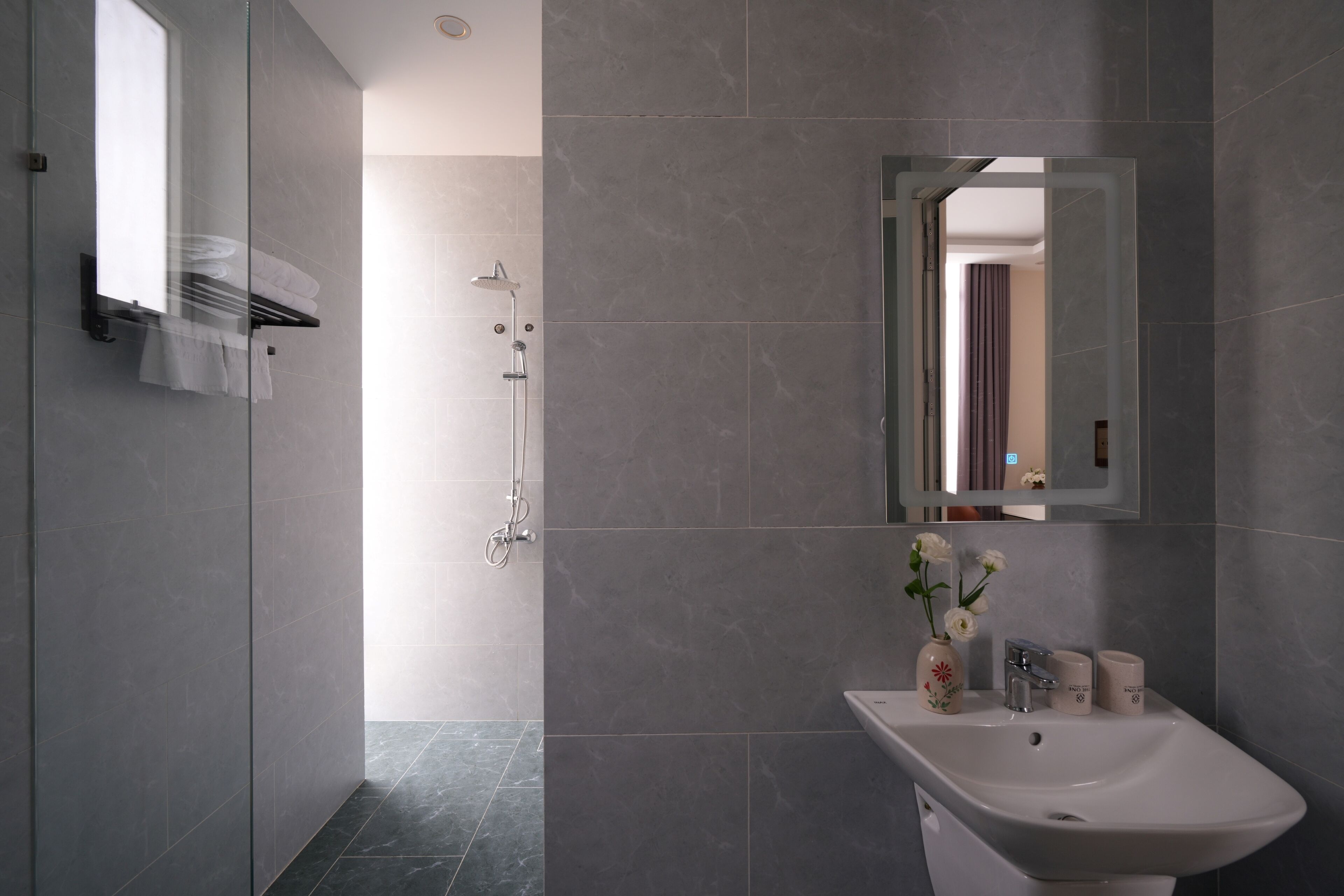 A modern bathroom with a shower, a sink, and a mirror.