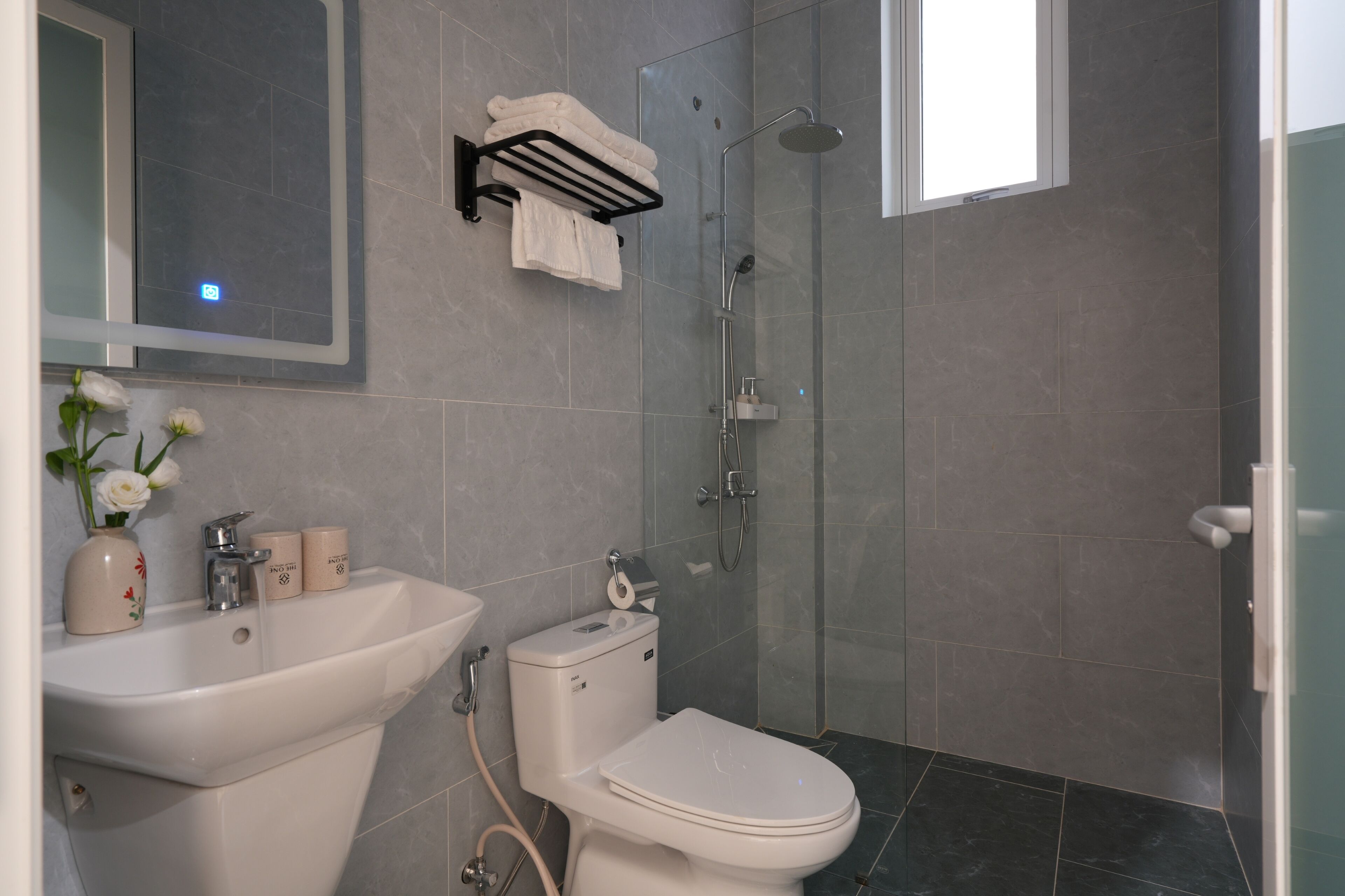 Een moderne badkamer met toilet, wastafel en douche.
