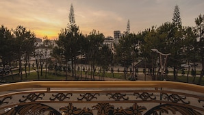 A balcony with a railing, overlooking a park with trees and a gazebo. - The One Da Lat Hotel (Xuan Huong - Da Lat)