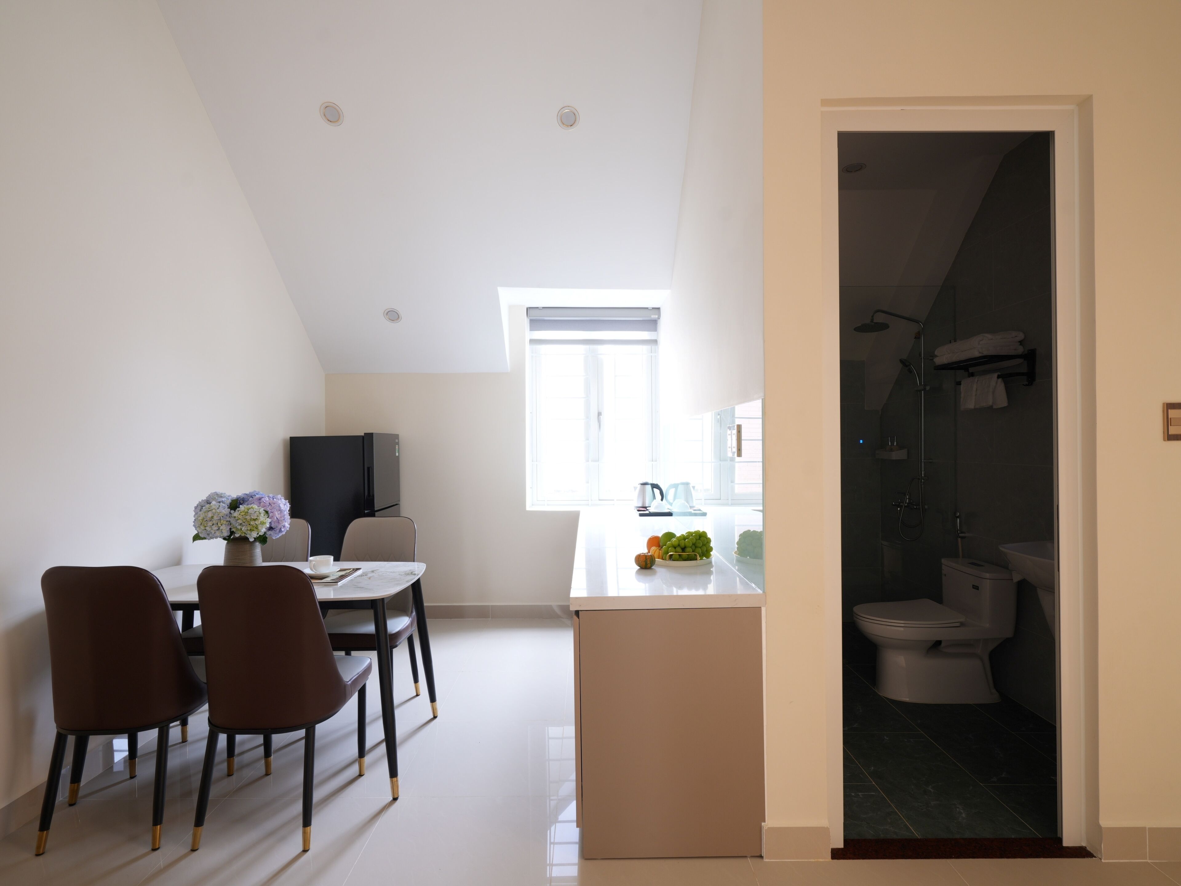 A compact kitchen with a dining area, a small refrigerator, and a window providing natural light.