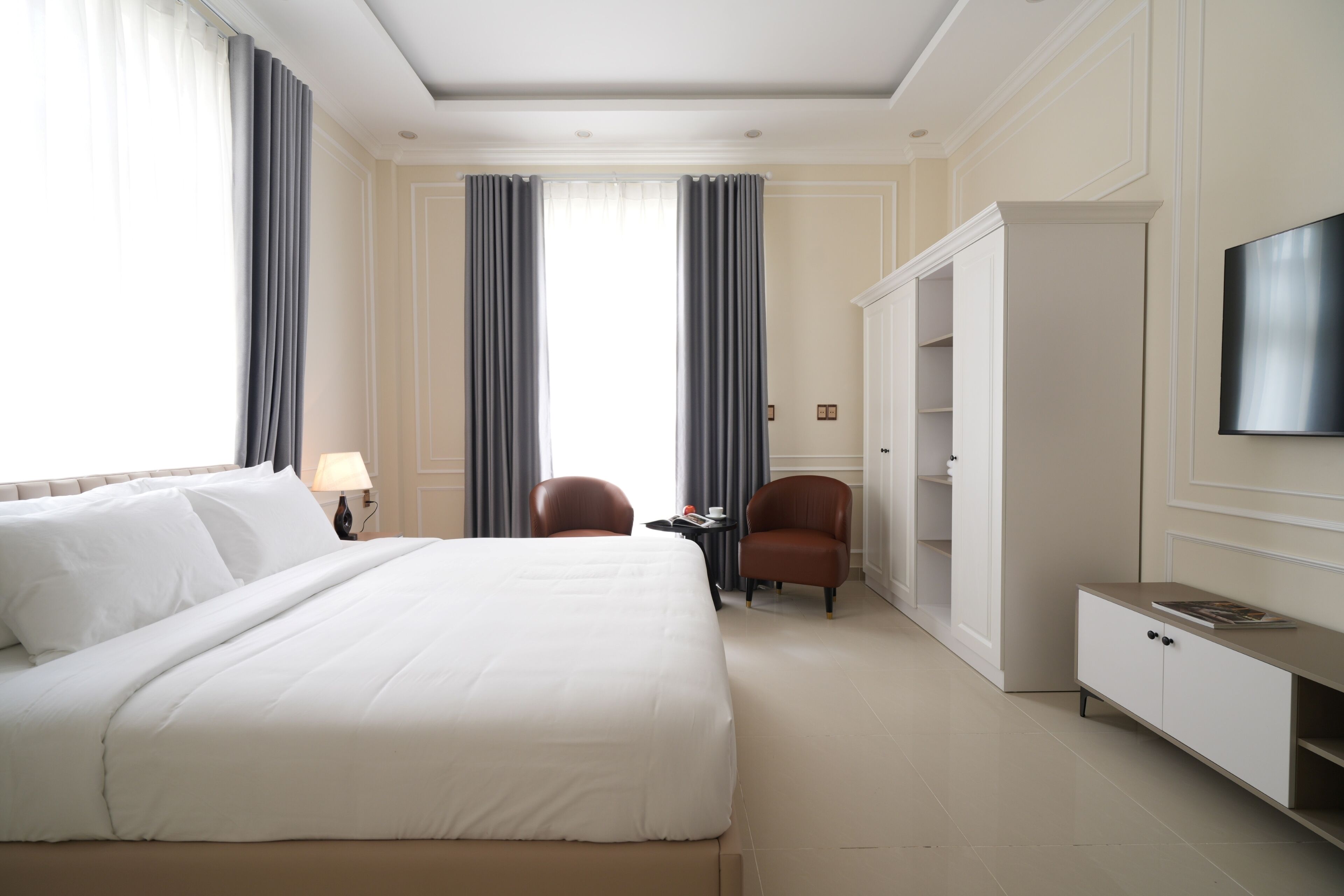 Una habitación de hotel con una cama grande, televisión, escritorio y armario.