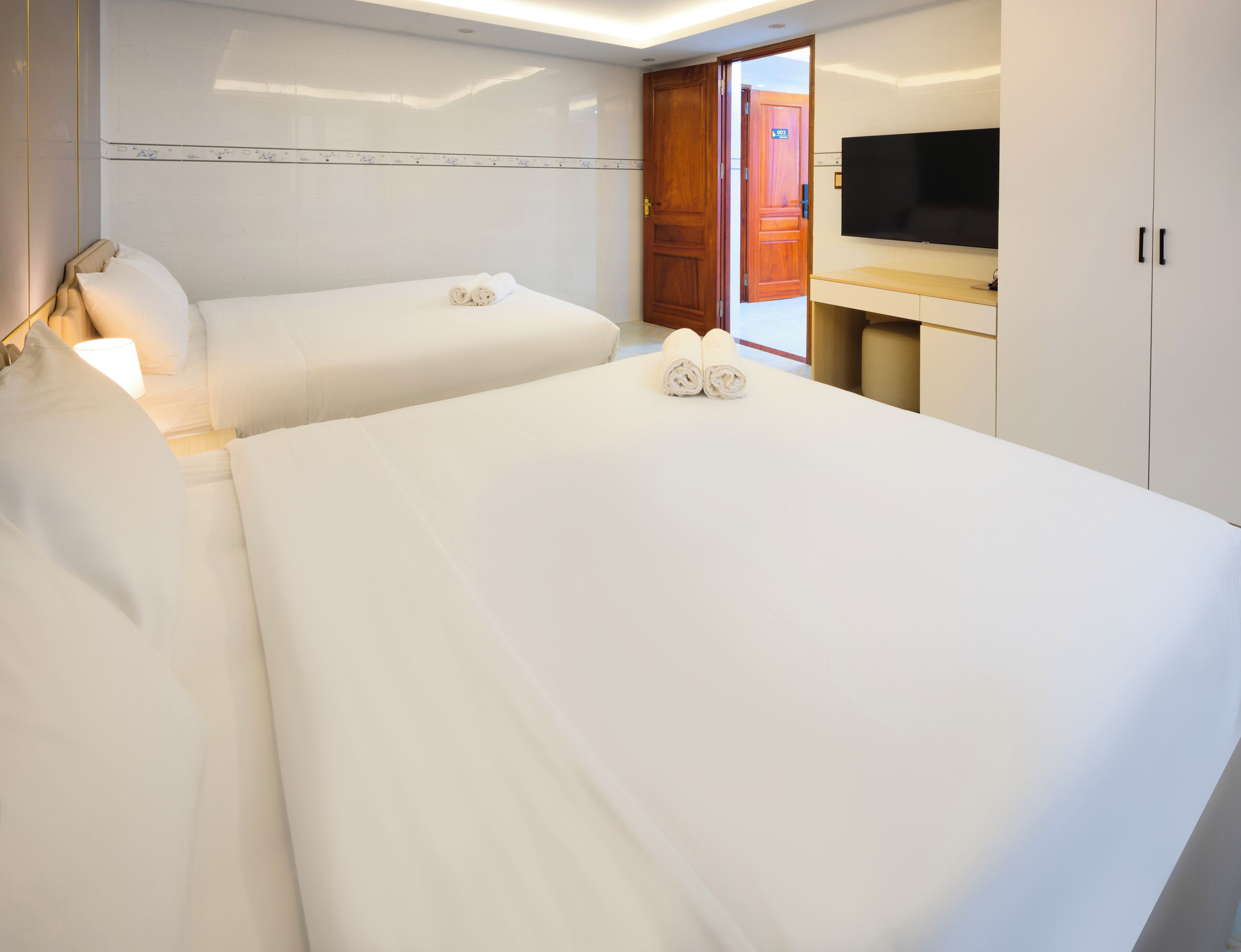 A hotel room with two beds, a TV, and a wooden door.