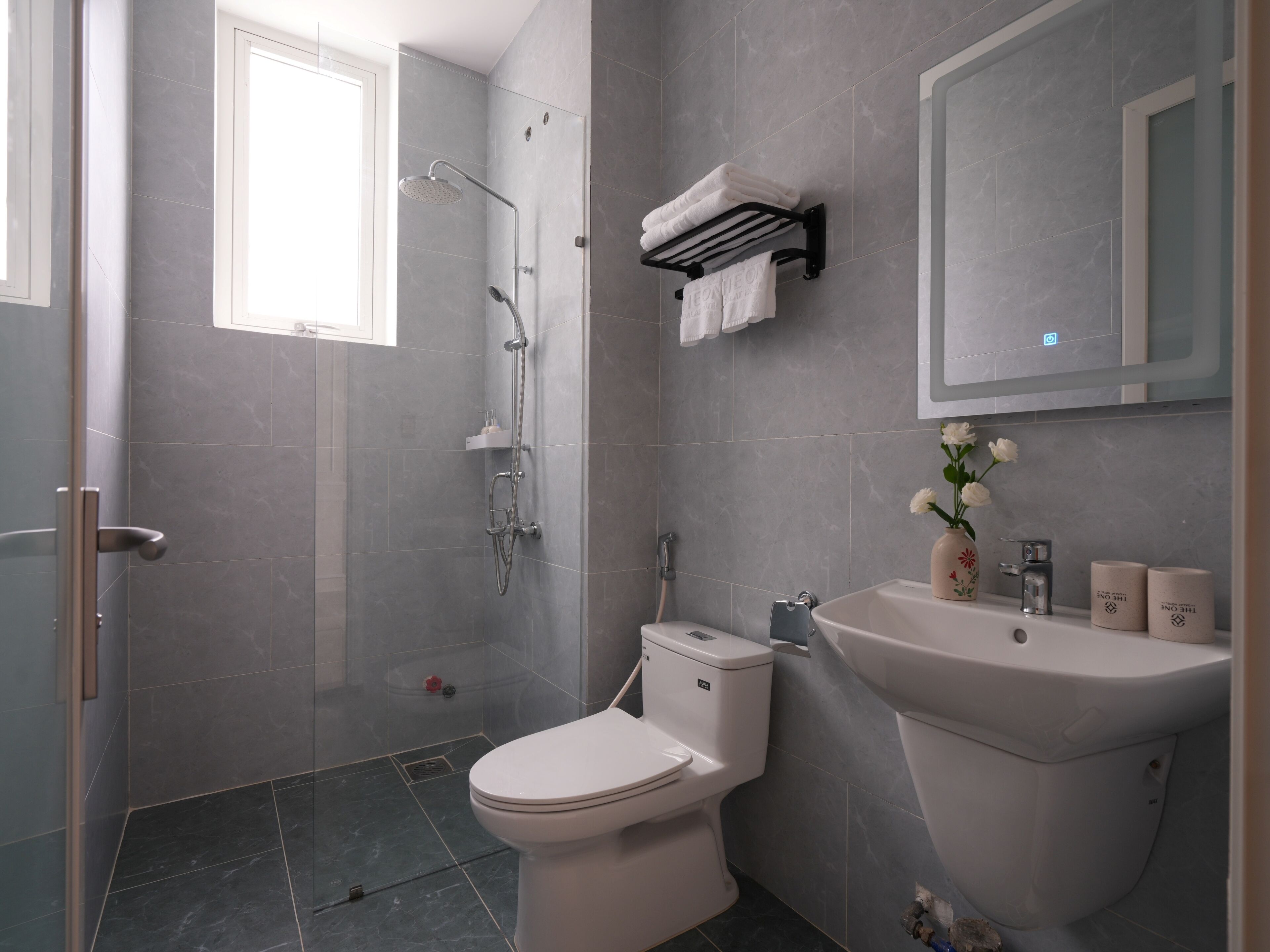 Un baño moderno con ducha, inodoro, lavamanos y espejo.