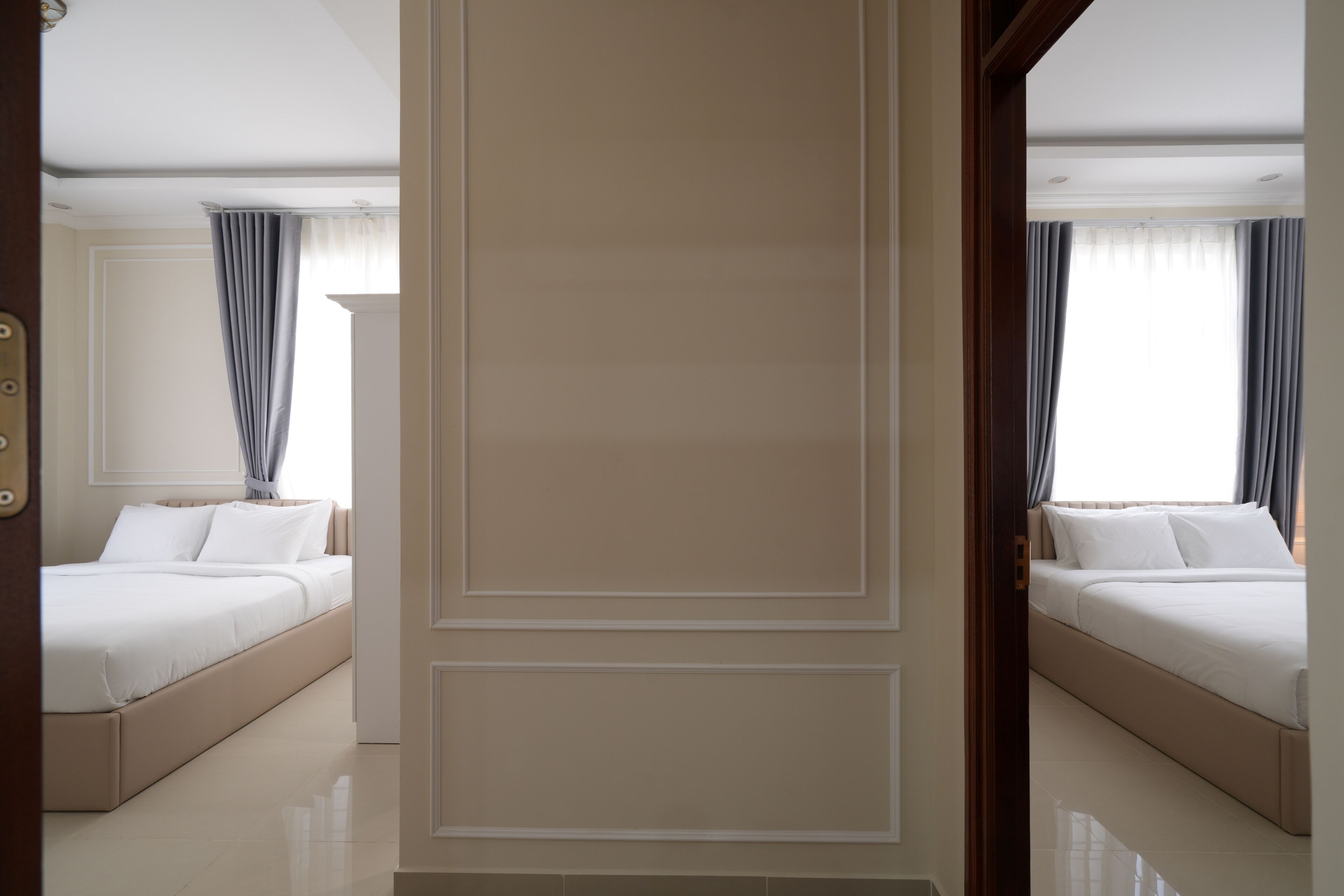 Hotellihuone, jossa on suuri sänky, erillinen oleskelualue ja ikkuna, jossa on verhot.