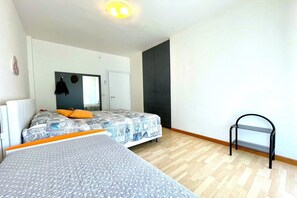 Quarto com cama, penteadeira, espelho e uma pequena estante preta.