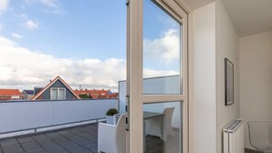 A modern apartment with a glass door leading to a balcony. The balcony has a white chair and a small table. - Holiday Home in Zoutelande near Sandy Beaches (Zoutelande)
