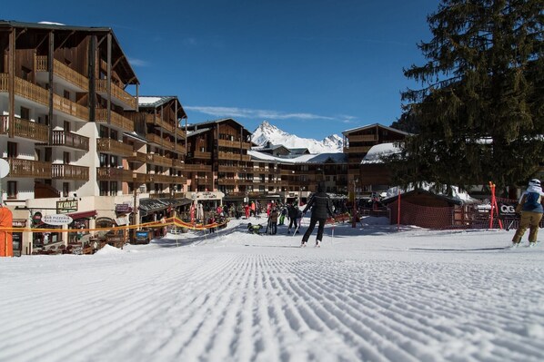 A ski resort with wooden buildings, a ski slope, and a mountain in the background.