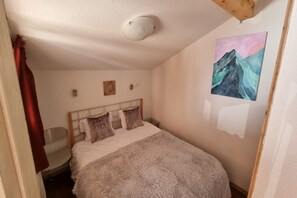 A bedroom with a bed, a painting on the wall, and a ceiling light. - Apartment in Valfréjus near Gondola (Modane)