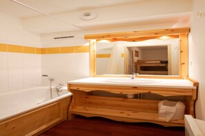 A bathroom with a wooden vanity, white sink, and a large mirror. - Apartment in Valfréjus near Gondola (Modane)