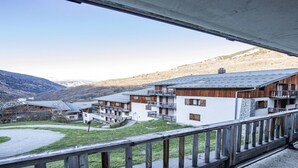 A hotel with multiple balconies, a courtyard, and a mountainous backdrop.
