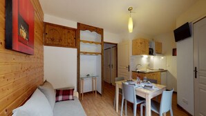 A compact living space with a wooden interior, a dining area, and a kitchenette. - Apartment in Orelle with ski storage (Orelle)