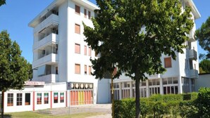 Un edificio de varios pisos con techo plano y un local comercial en la planta baja.