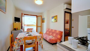 Una cocina compacta con una mesa, sillas, un sofá y un refrigerador pequeño.