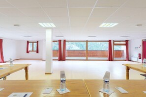 A conference room with large windows, wooden tables, and water bottles on placemats.