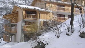 Una cabaña de madera con varios balcones, ubicada en una zona montañosa nevada.