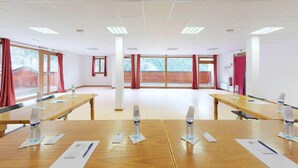 Un salón de conferencias con mesas de madera, botellas de agua y documentos.