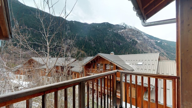 A wooden cabin with a balcony, surrounded by mountains and trees. - Apartment in Orelle with Pool & Sauna (Orelle)