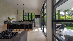 A modern kitchen with a central island, bar stools, and a dining area with a table and chairs.