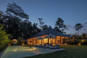 Une maison moderne dotée d’une piscine, d’un espace salon extérieur et d’un patio couvert.