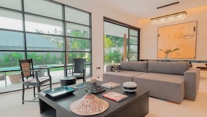 A modern living room with a grey sofa, a black coffee table with decorative items, and a large abstract painting on the wall.