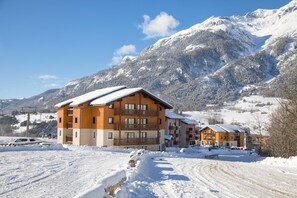 A multi-story wooden building with balconies, surrounded by snow-covered mountains and a clear sky. - Apartment in Val Cenis near Ski area (Val Cenis)