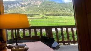 Une chambre avec vue sur un champ verdoyant et des montagnes.