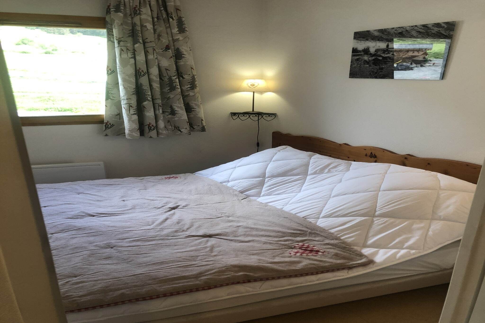 A bed with a white quilted mattress, a wooden headboard, and a bedside lamp.