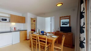 Una cocina compacta con armarios de madera, un microondas y un comedor con mesa y sillas.