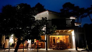 A two-story building with a balcony and a dining area with chairs and tables. - Laguillotte- 3 bedrooms (Seignosse)