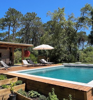 A swimming pool with lounge chairs and a pergola with an umbrella. - Laguillotte- 3 bedrooms (Seignosse)