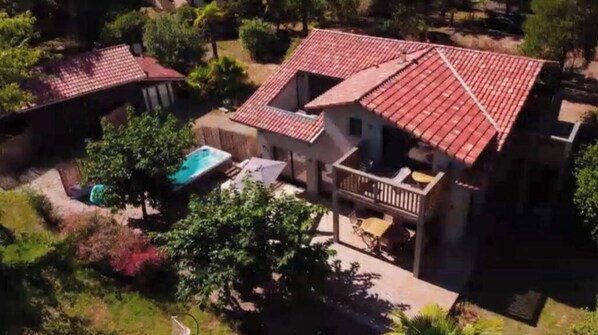 Una propiedad residencial con techo de tejas rojas, piscina y un patio cubierto.