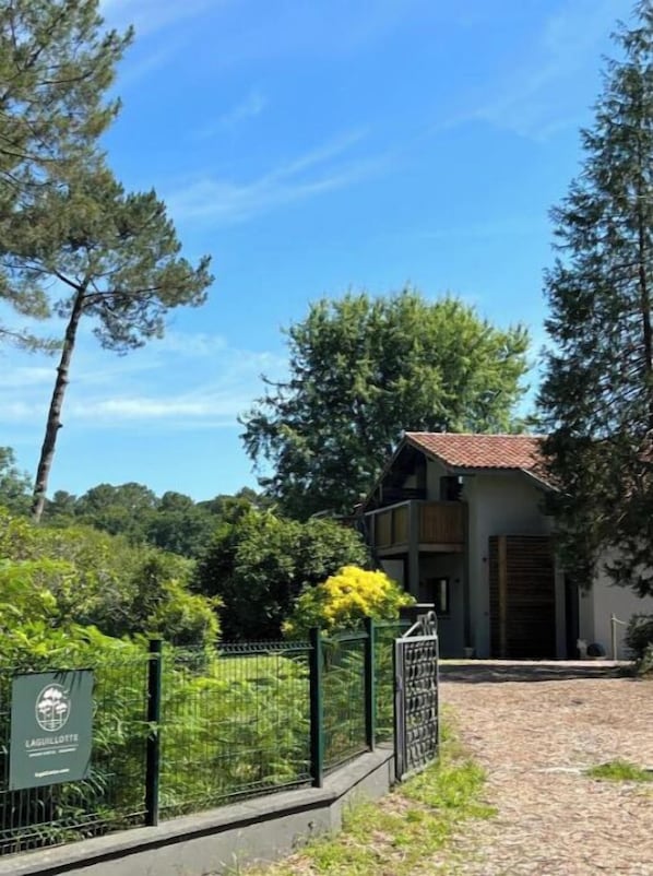 A building with a tiled roof, surrounded by lush greenery and trees. - Laguillotte- 3 bedrooms (Seignosse)