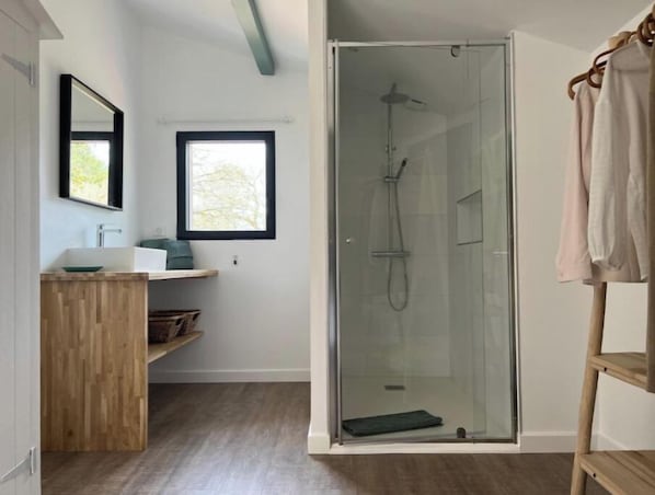 Un bagno moderno con doccia a vetro, mobile lavabo in legno, finestra e porta asciugamani.