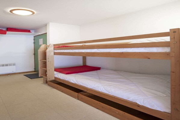 A bunk bed with a red mat and a white mattress.