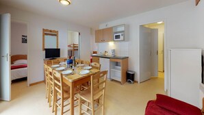 Ett kompakt bostadsutrymme med en matplats, ett litet kök och en säng.