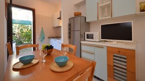 Cocina compacta con una mesa de comedor, sillas, microondas y televisor.
