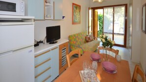 Cocina compacta con microondas, un televisor pequeño y comedor con mesa dispuesta para dos.