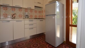 A kitchen with white cabinets, a stainless steel refrigerator, a coffee maker, and a patterned floor.