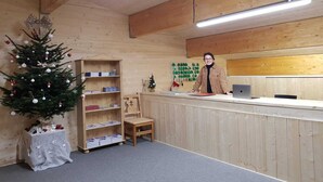 Een houten receptiebalie met een kerstboom, boekenplanken en een laptop.