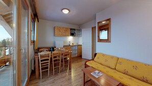 Un espacio habitable compacto con comedor, kitchenette y sofá.