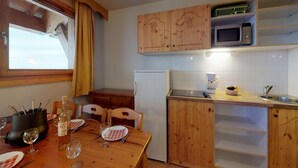 Cocina compacta con armarios de madera, un microondas y un lavamanos.