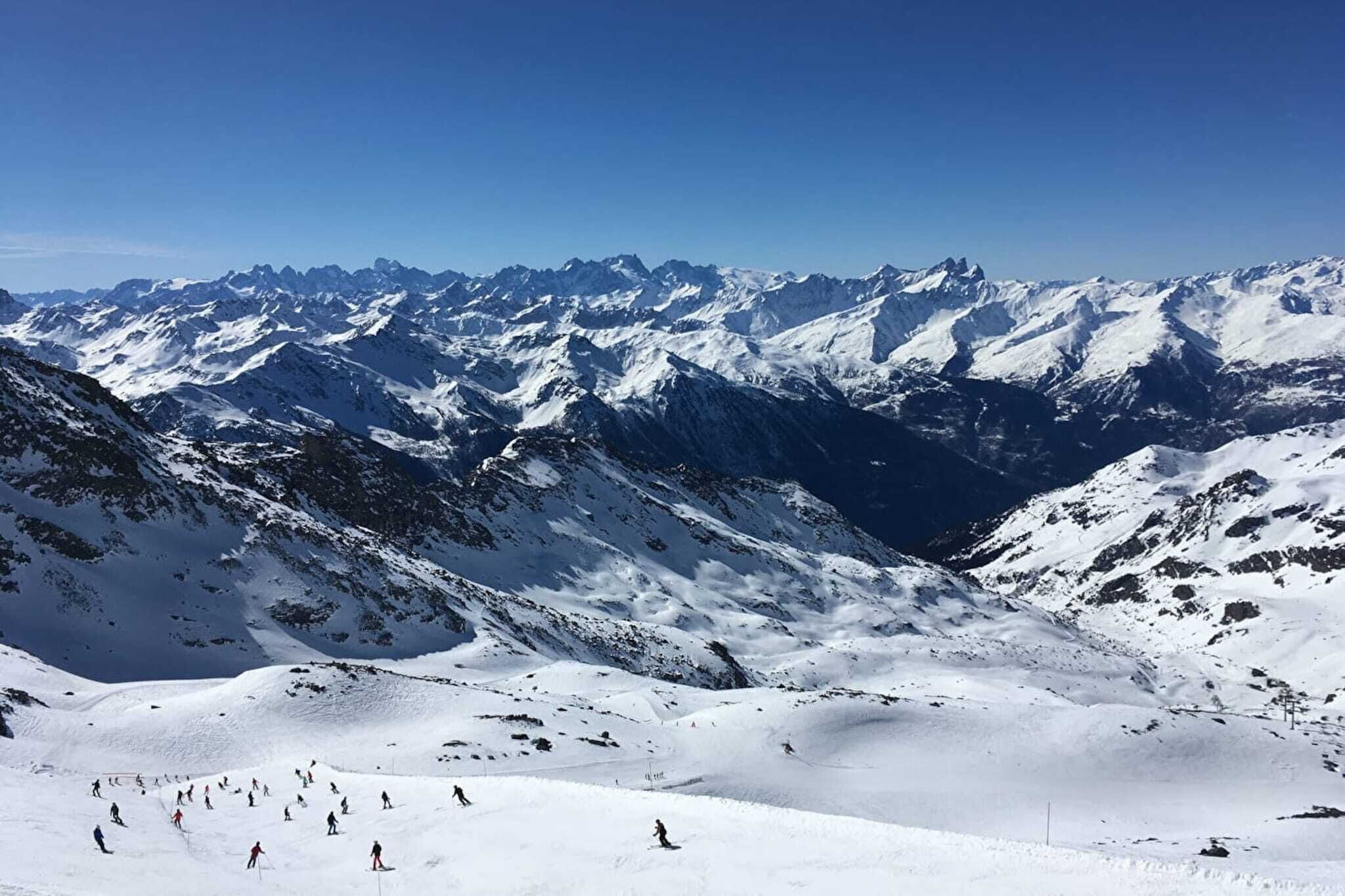 A snow-covered mountain landscape with skiers.