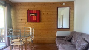 Una habitación con pared de paneles de madera, una mesa de vidrio con sillas, un sofá de cuero marrón y un espejo.
