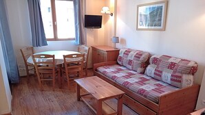 A cozy room with a wooden sofa, a small wooden table, and a round dining table with chairs. - Apartment for 6 people in Val Cenis (Val Cenis)