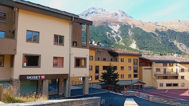 A multi-story building with a ski resort sign, a covered outdoor area, and a mountain backdrop. - Apartment for 6 people in Val Cenis (Val Cenis)